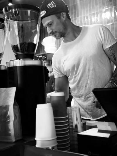 Black-and-white portrait of Richie Conry behind the grinder — owner of Moon Wolf Black-and-white portrait of Richie Conry behind the grinder — owner of Moon Wolf