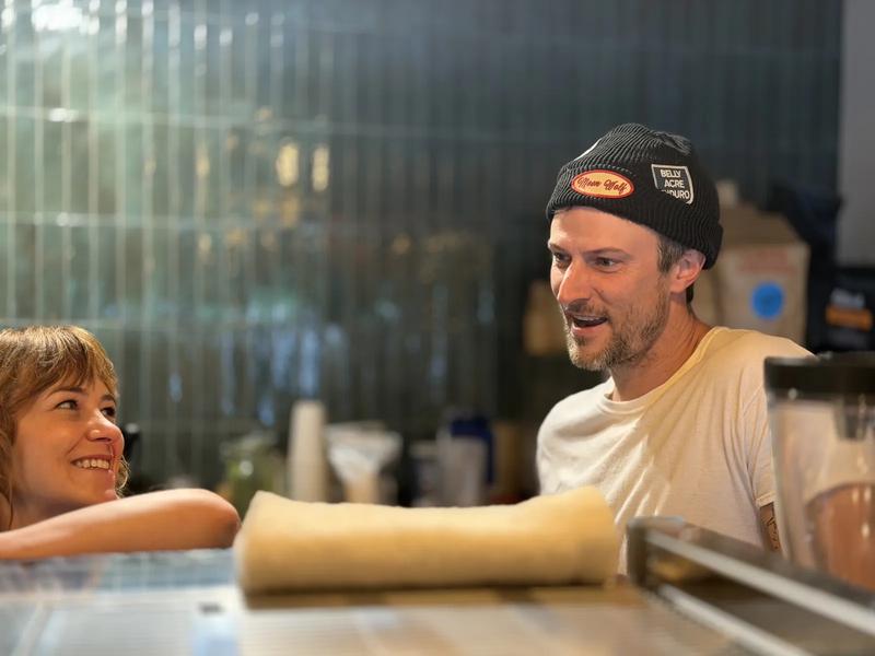 Behind the Moon Wolf bar — Richie in a Moon Wolf beanie chatting with a customer mid-shift Behind the Moon Wolf bar — Richie in a Moon Wolf beanie chatting with a customer mid-shift