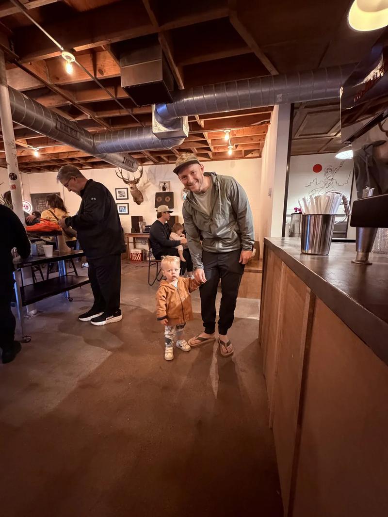 Richie with a toddler customer at Moon Wolf — multigenerational opening-week scene Richie with a toddler customer at Moon Wolf — multigenerational opening-week scene